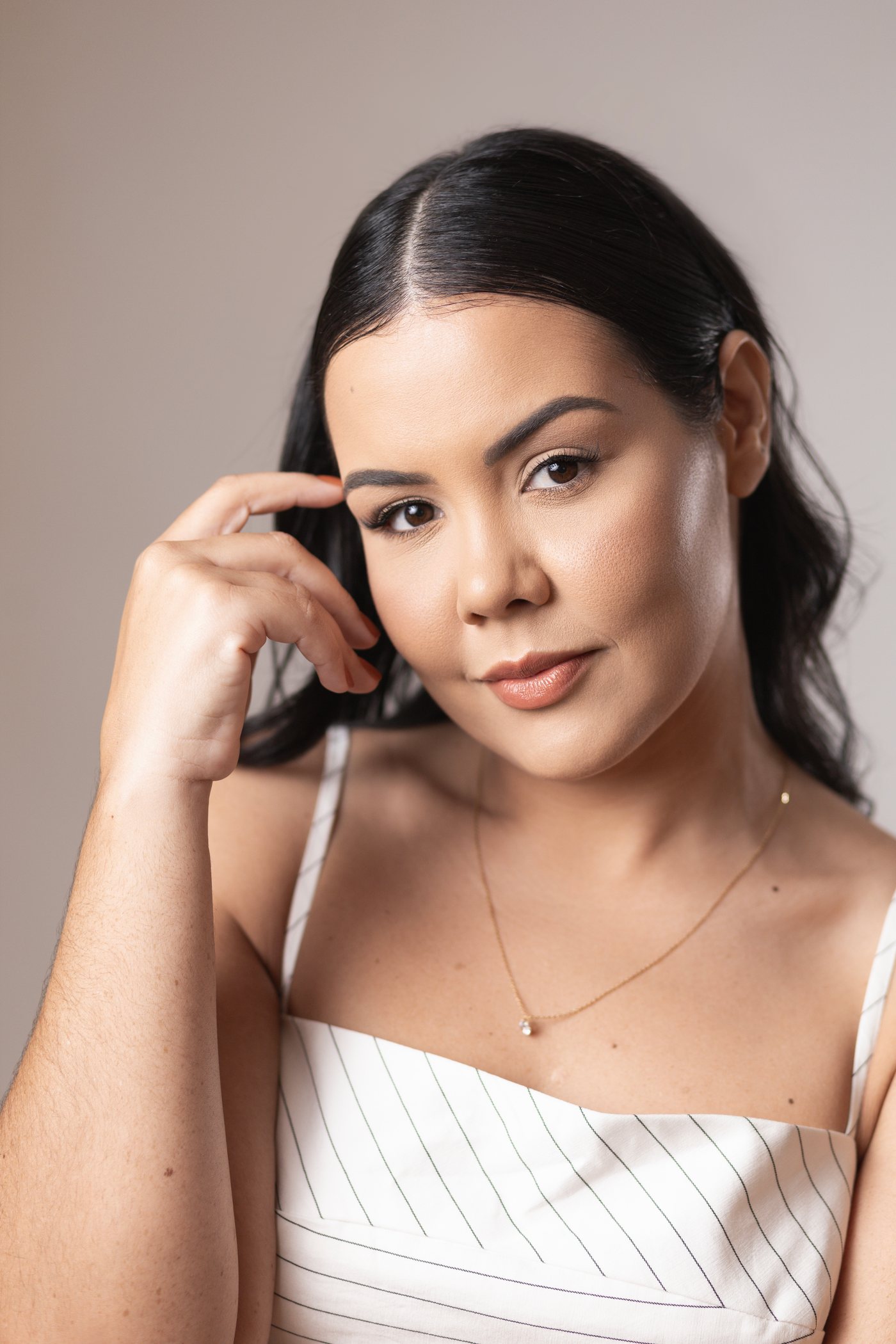 Jennedy Lima em retrato de estúdio, a mão apoiada na têmpora, olhando para a câmera.